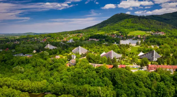 Ustroń i okolice co zwiedzić? Widok z lotu ptaka na zielone wzgórza, charakterystyczne budynki i lasy.