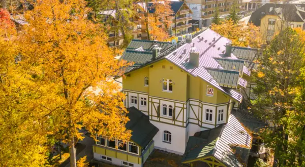 Jesienny hotel w Szklarskiej Porębie otoczony złotymi drzewami. Widok z góry na architekturę górską.