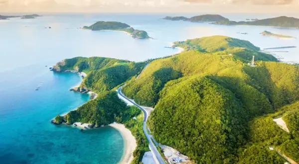 Malownicze Japonia plaże z turkusową wodą i zielonymi wzgórzami. Droga wije się wśród bujnej roślinności, prowadząc do ukrytych zatoczek.
