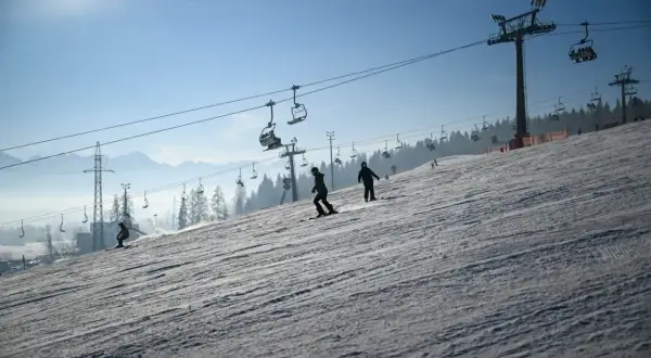 Narciarze i snowboardziści korzystają z wyciągów krzesełkowych na stoku. Białka Tatrzańska oferuje wspaniałe atrakcje zimą.