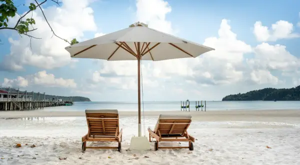 Dwie leżaki pod parasolem na piaszczystej plaży. Idealne miejsce, by zapytać, gdzie na wakacje w czerwcu.