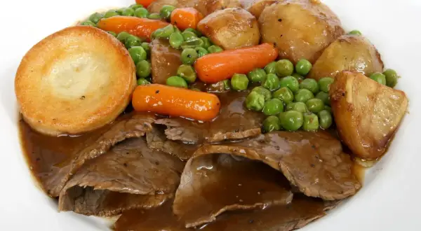Tradycyjne jedzenie w Wielkiej Brytanii: pieczona wołowina, ziemniaki Yorkshire, marchewka i groszek w sosie.