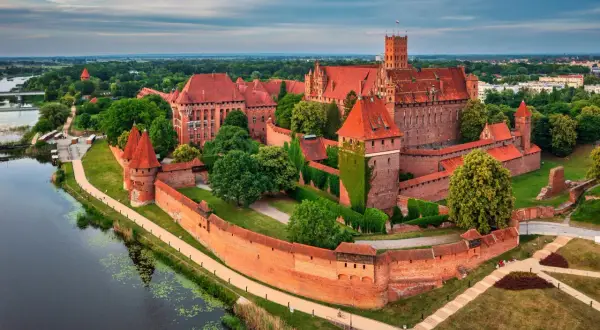 Malbork, największy zamek w Polsce, majestatycznie wznosi się nad rzeką Nogat. Jego ceglane mury i wieże świadczą o bogatej historii.