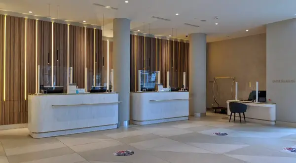 Eleganckie recepcje w Radisson Collection Hotel Warsaw, z nowoczesnym oświetleniem i marmurowymi blatami, zapraszają do komfortowego zameldowania.