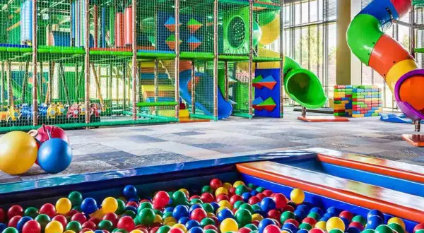 Kolorowa sala zabaw z basenem pełnym piłek i zjeżdżalniami. Idealne miejsce dla dzieci w rodzinnym hotelu nad morzem.