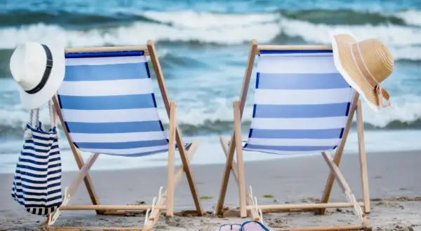 Dwa leżaki na plaży, gotowe na relaks. Idealne atrakcje nad morzem dla każdego, kto szuka słońca i fal.