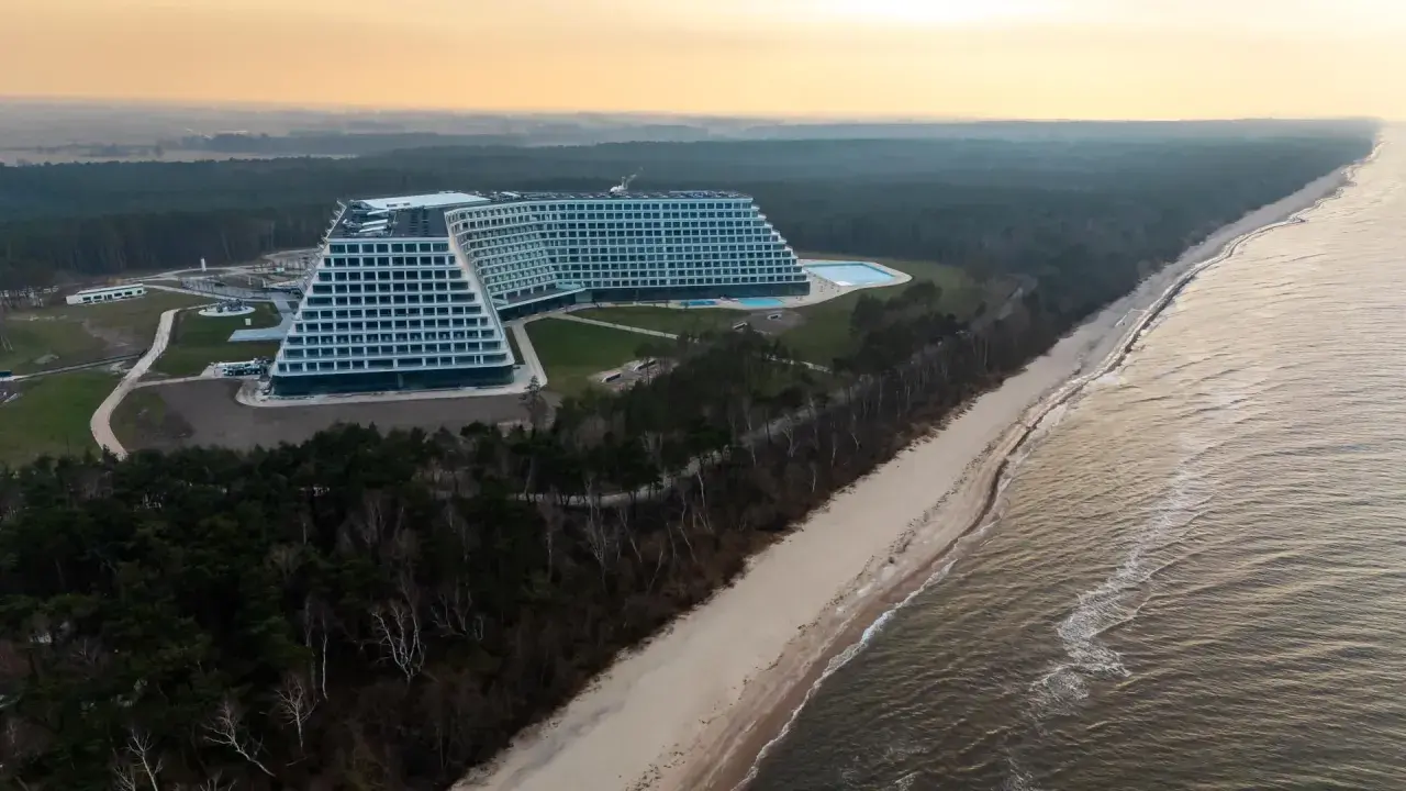 Nowo otwarty hotel nad morzem, z basenem i widokiem na plażę i las. Architektura przypomina schody.