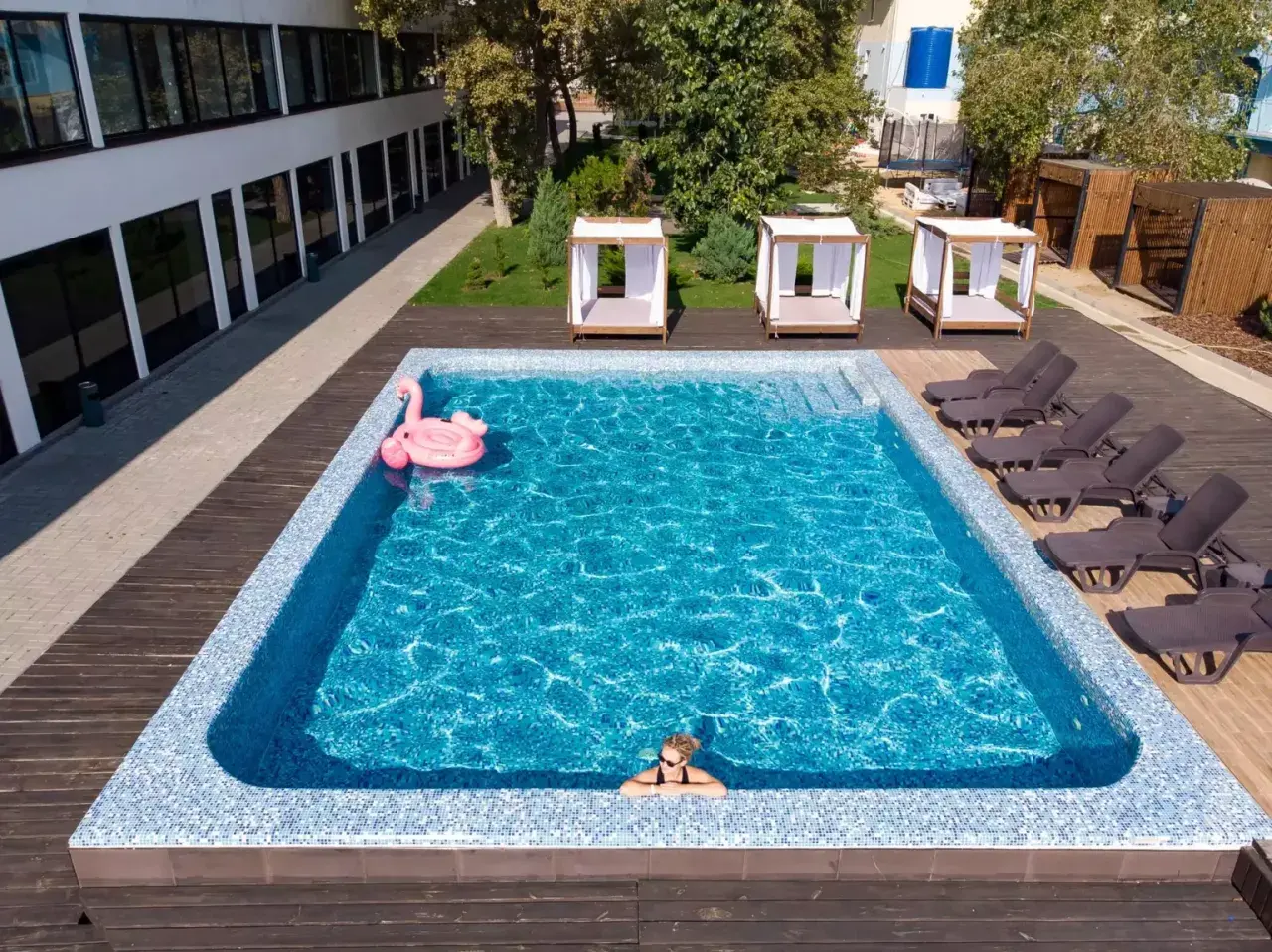 Relaks w basenie w hotelu w Karpaczu. Różowy flaming unosi się na wodzie, a obok leżaki i zaciszne altanki. Idealne miejsce na wakacje.