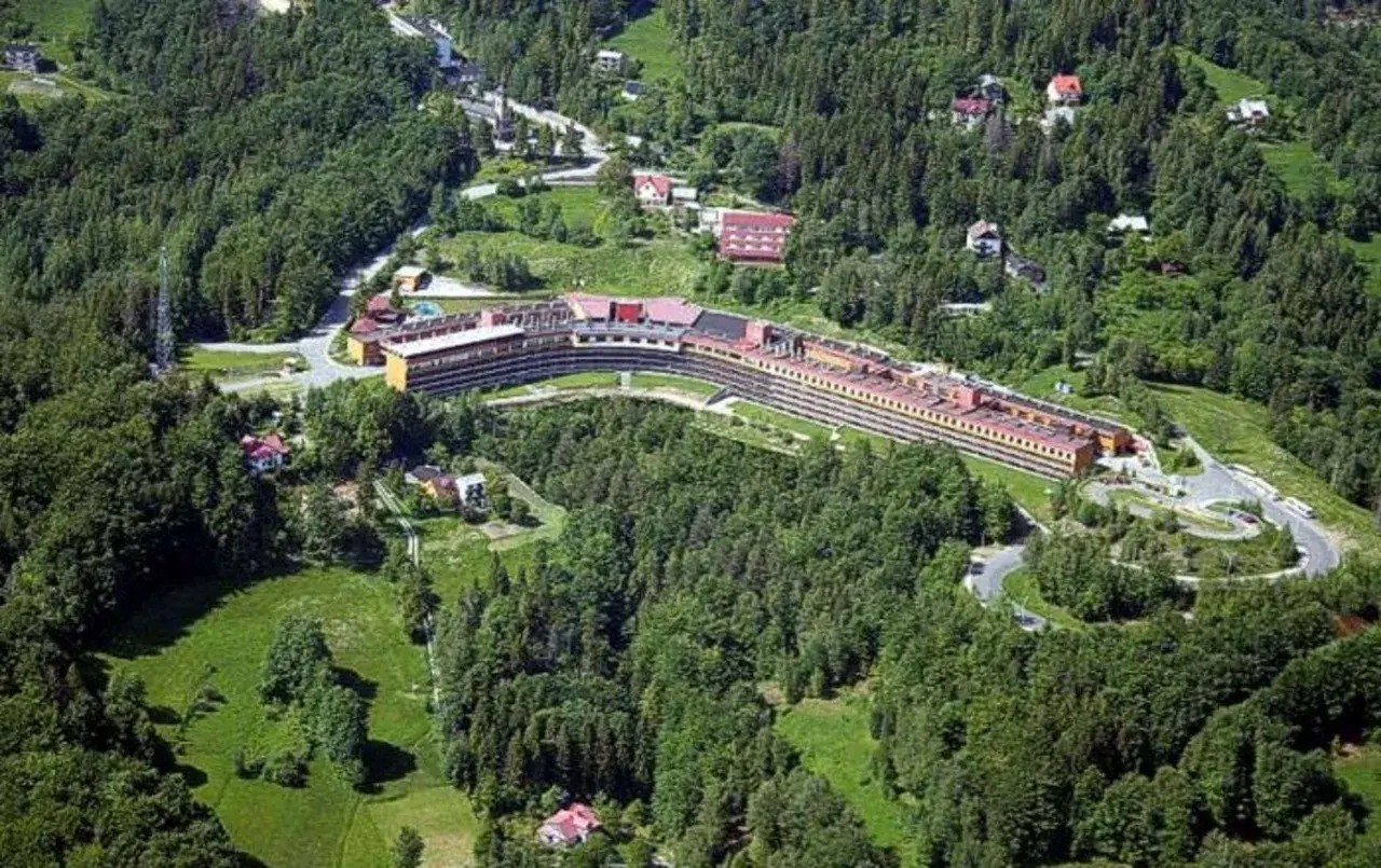 Widok z lotu ptaka na Orle Gniazdo w Szczyrku, rozległy budynek hotelowy otoczony zielonymi lasami i polanami.
