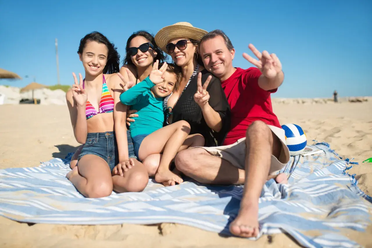Rodzina cieszy się wakacjami z dziećmi w Polsce na plaży. Wszyscy pozdrawiają, pokazując znak pokoju.