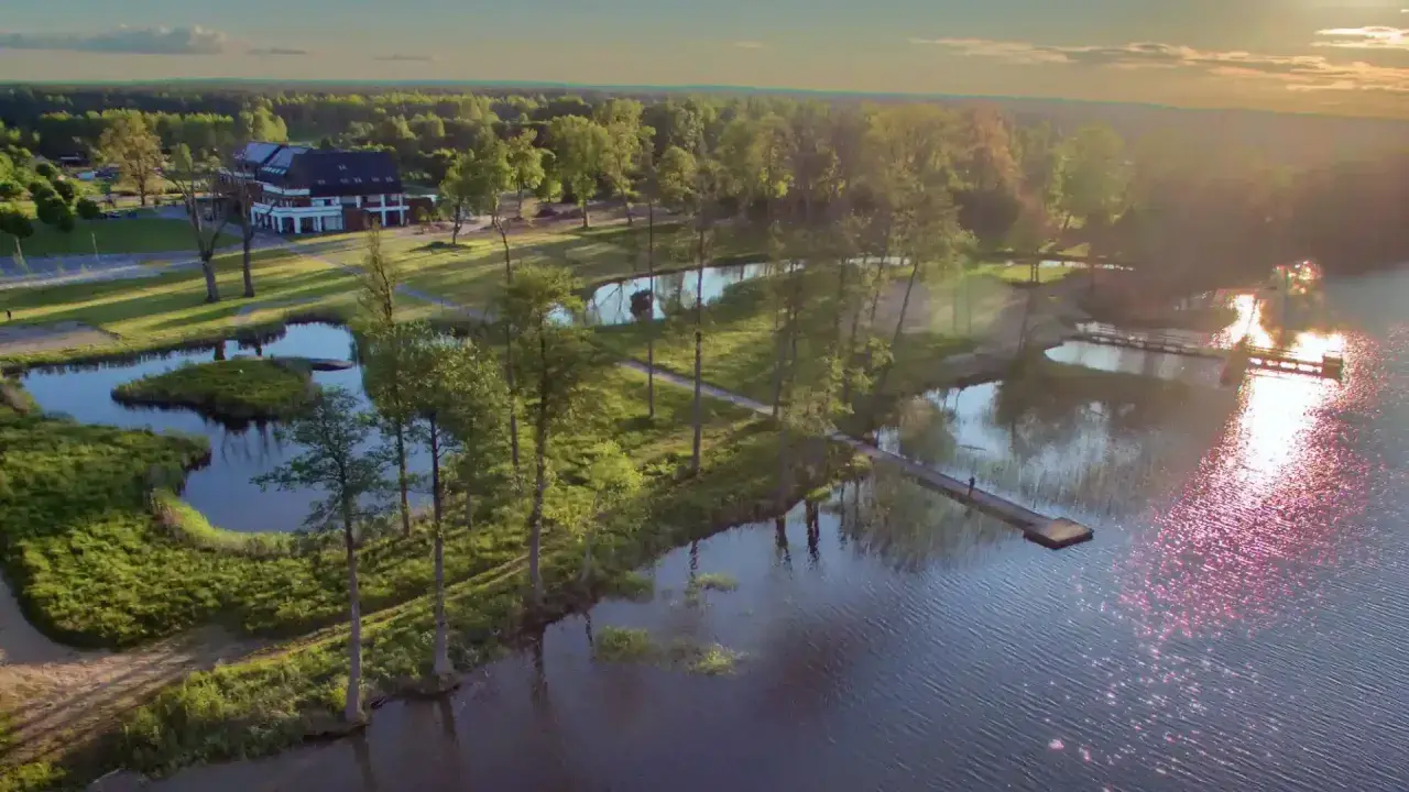Malownicze mazury miejscowości nad jeziorem. Hotel z pomostami i zielenią, idealne miejsce na wypoczynek.