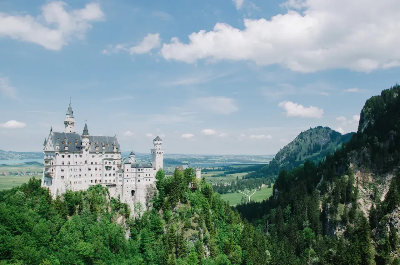 Bajkowy zamek Neuschwanstein, jeden z najpiękniejszych zamków w Europie, wznosi się na skalistym wzgórzu otoczonym zielonymi lasami.