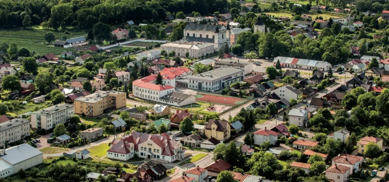 Widok z lotu ptaka na Janów Podlaski. Widać zabudowania, kościół i tereny zielone. Atrakcje tego miejsca zachęcają do odwiedzin.