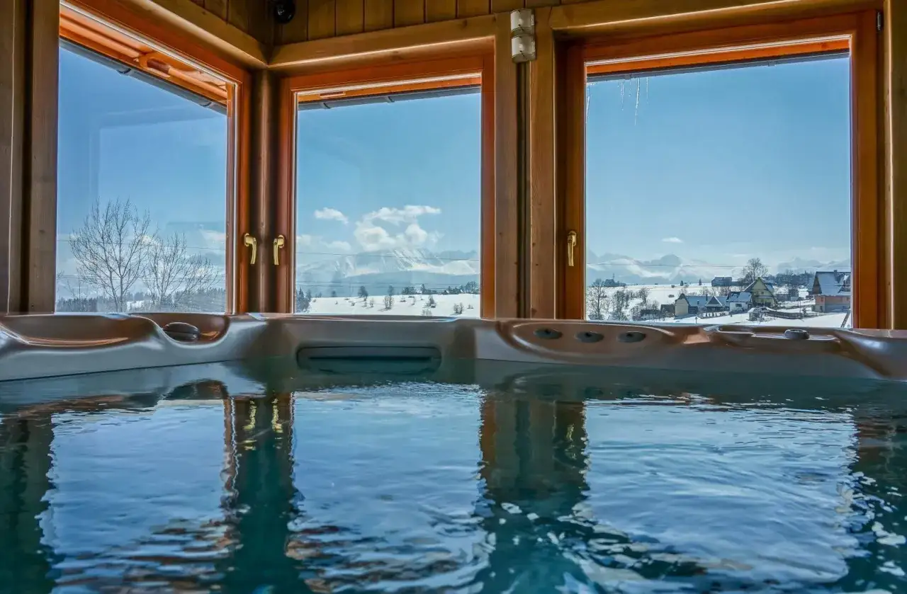 Relaks w jacuzzi z widokiem na zimowy krajobraz. Idealne miejsce na voucher na weekend w spa dla dwojga.