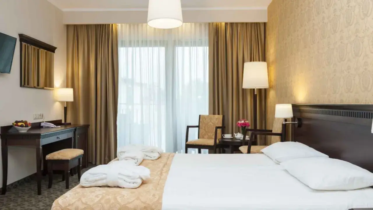 Przytulny pokój hotelowy z łóżkiem, biurkiem i dwoma fotelami. Idealne miejsce na wypoczynek podczas podróży, jak w najlepszych hotelach za granicą.