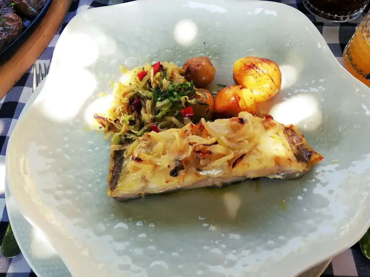 Pieczona ryba z cebulą, ziemniakami i surówką. Pyszne portugalskie przysmaki na talerzu.