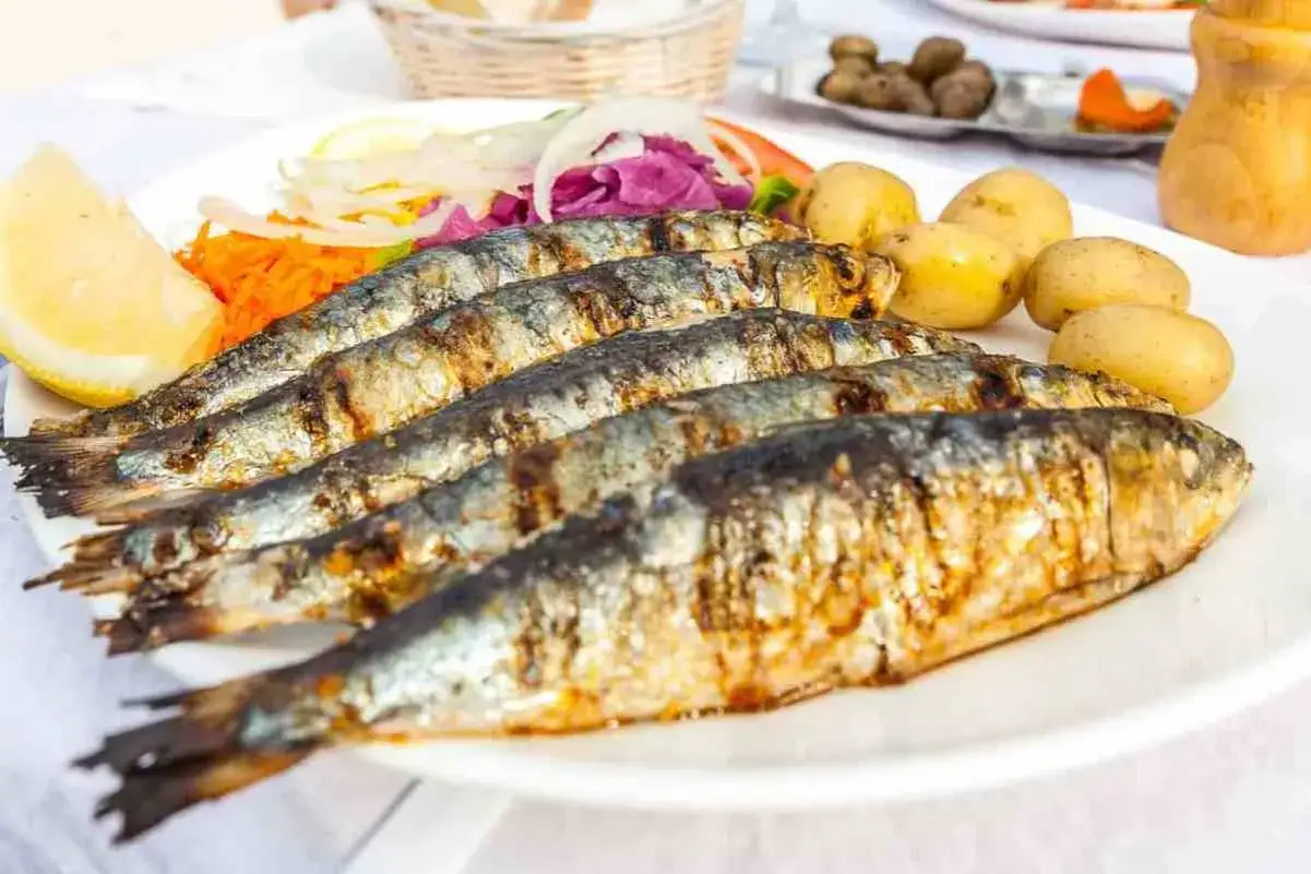 Grillowane sardynki z ziemniakami i sałatką, klasyczne portugalskie jedzenie.
