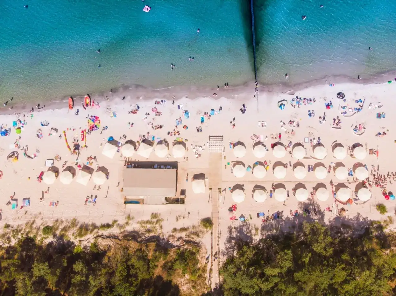 Plaża w Polsce, pełna słońca i ludzi. Idealne miejsce na wakacje all inclusive, gdzie każdy znajdzie coś dla siebie.