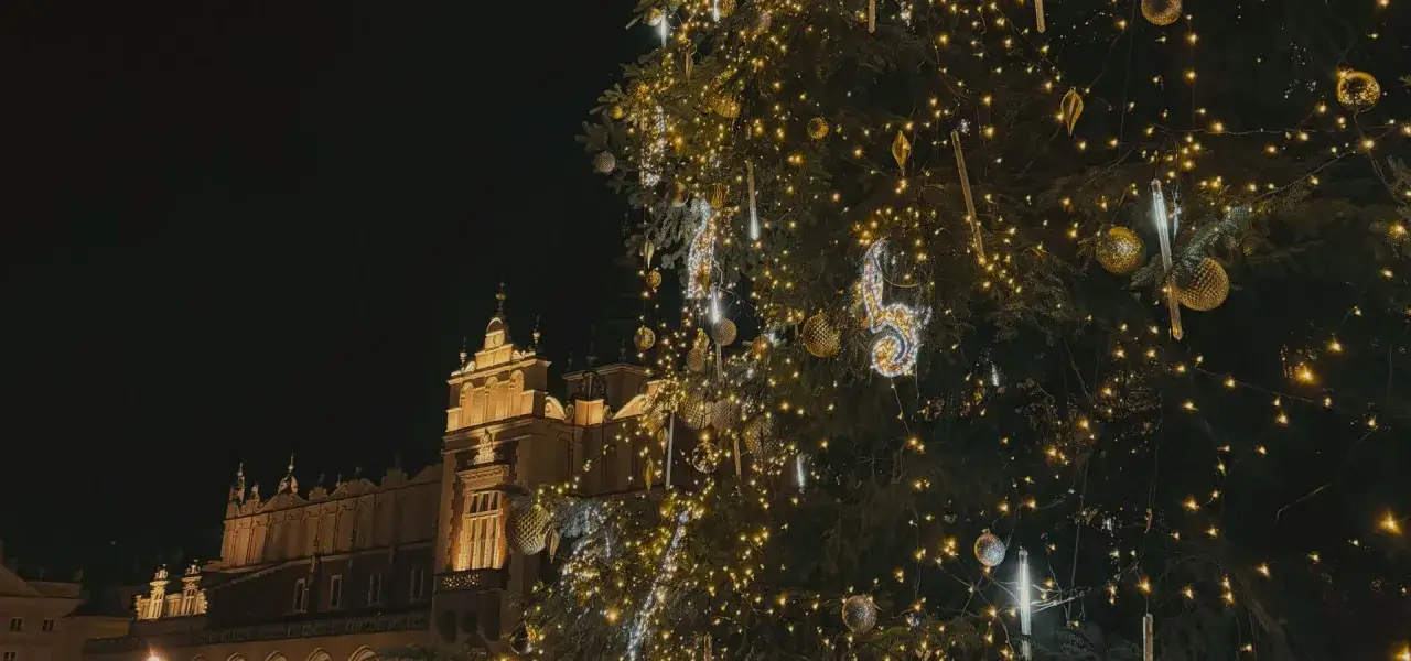 Kraków atrakcje zimą: rozświetlona choinka i Sukiennice nocą tworzą magiczny klimat.