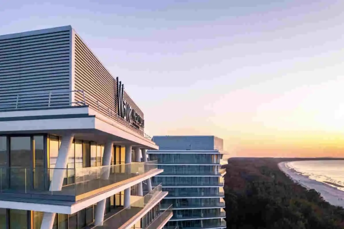 Nowo otwarty hotel nad morzem, z nowoczesną architekturą i widokiem na plażę o zachodzie słońca.
