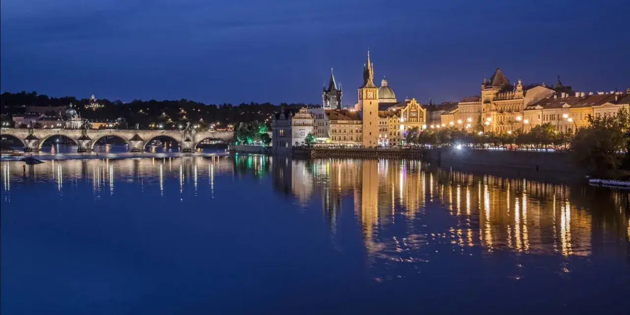 Nocna panorama Pragi z Mostem Karola i odbijającymi się w Wełtawie światłami. Wiele ciekawostek czeka na odkrycie!