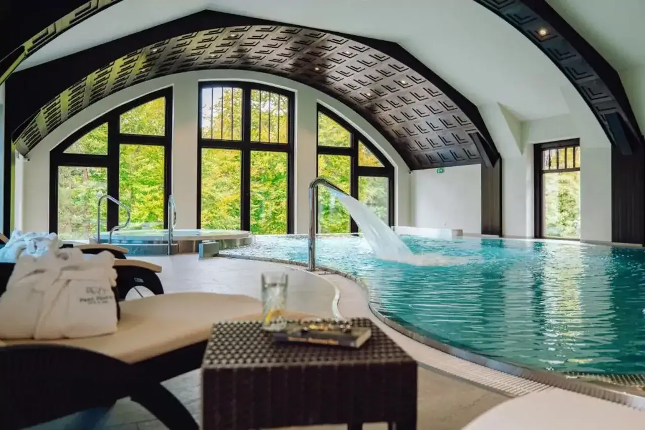 Relaks w basenie z wodospadem i jacuzzi. Idealne spa dla dorosłych, z widokiem na zieleń.