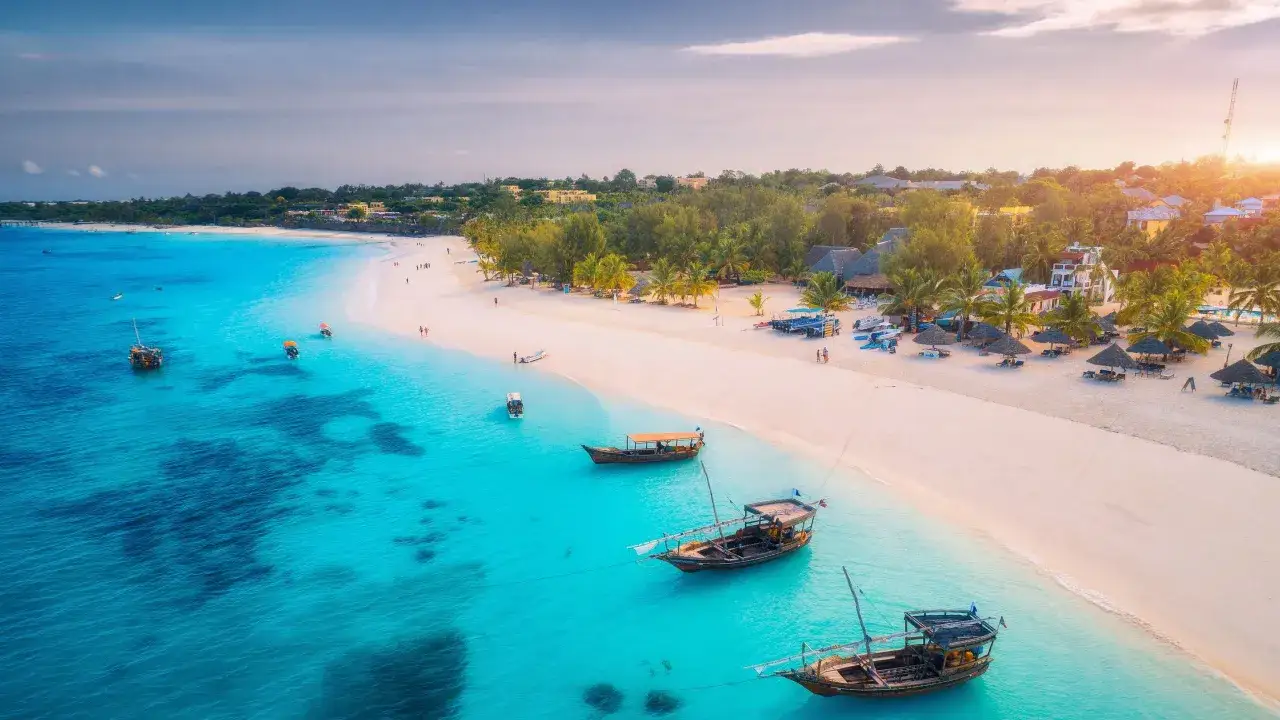 Piękna plaża z turkusową wodą i łodziami, idealne miejsce, by zastanowić się, kiedy lecieć na Zanzibar.