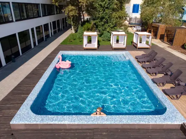 Relaks w basenie w hotelu w Karpaczu. Różowy flaming unosi się na wodzie, a obok leżaki i zaciszne altanki. Idealne miejsce na wakacje.
