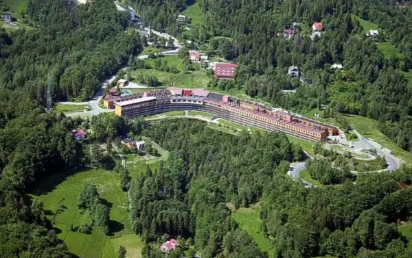 Widok z lotu ptaka na Orle Gniazdo w Szczyrku, rozległy budynek hotelowy otoczony zielonymi lasami i polanami.