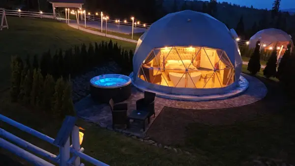 Nocny widok na hotel na szczycie góry. Dwie kopuły, jedna z wanną i łóżkiem, druga z jacuzzi na zewnątrz.