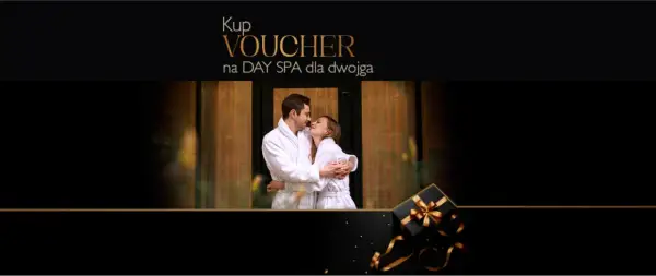 Para dwojga w szlafrokach przytulająca się na tle drewnianych drzwi. Obok czarny prezent ze złotą wstążką. Idealny voucher na weekend w spa dla dwojga.