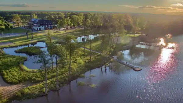 Malownicze mazury miejscowości nad jeziorem. Hotel z pomostami i zielenią, idealne miejsce na wypoczynek.