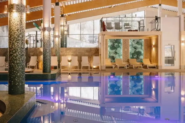 Basen w hotelu z leżakami i widokiem na góry.