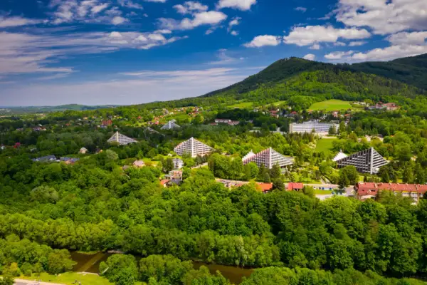 Ustroń i okolice co zwiedzić? Widok z lotu ptaka na zielone wzgórza, charakterystyczne budynki i lasy.
