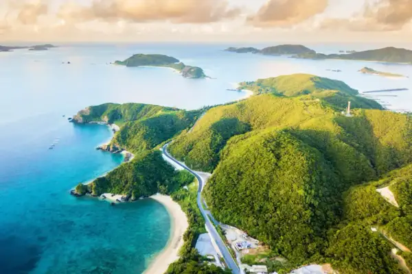 Malownicze Japonia plaże z turkusową wodą i zielonymi wzgórzami. Droga wije się wśród bujnej roślinności, prowadząc do ukrytych zatoczek.