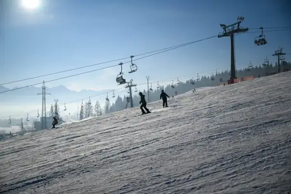 Narciarze i snowboardziści korzystają z wyciągów krzesełkowych na stoku. Białka Tatrzańska oferuje wspaniałe atrakcje zimą.