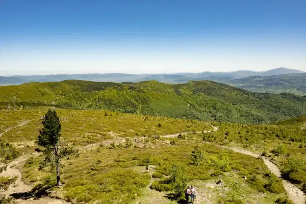 Malowniczy szlak na Baranią Górę, wijący się przez zielone wzgórza Beskidu Śląskiego. Dwoje turystów podziwia panoramę.