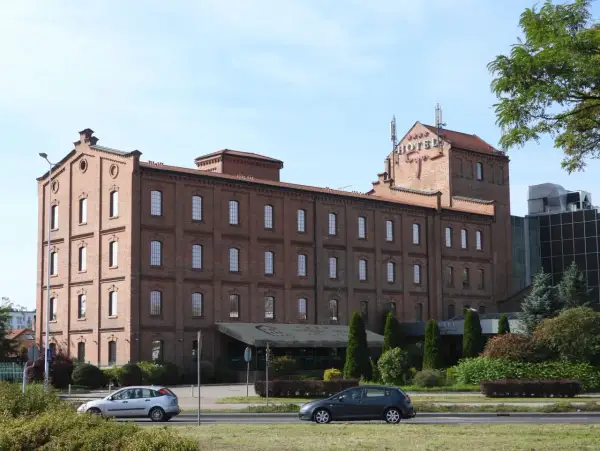 Hotel Młyn we Włocławku, ceglany budynek z czerwonym napisem HOTEL na dachu, otoczony zielenią.
