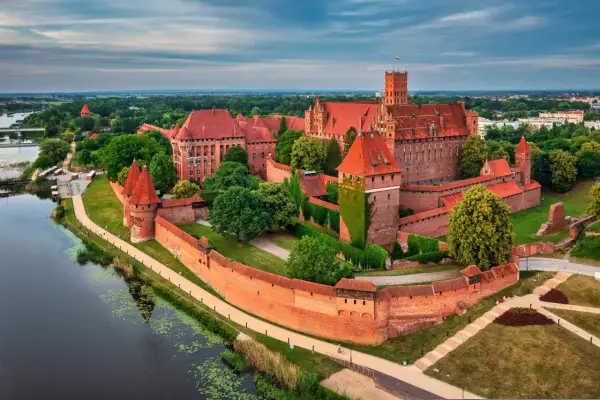 Malbork, największy zamek w Polsce, majestatycznie wznosi się nad rzeką Nogat. Jego ceglane mury i wieże świadczą o bogatej historii.