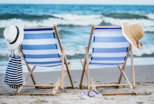 Dwa leżaki na plaży, gotowe na relaks. Idealne atrakcje nad morzem dla każdego, kto szuka słońca i fal.